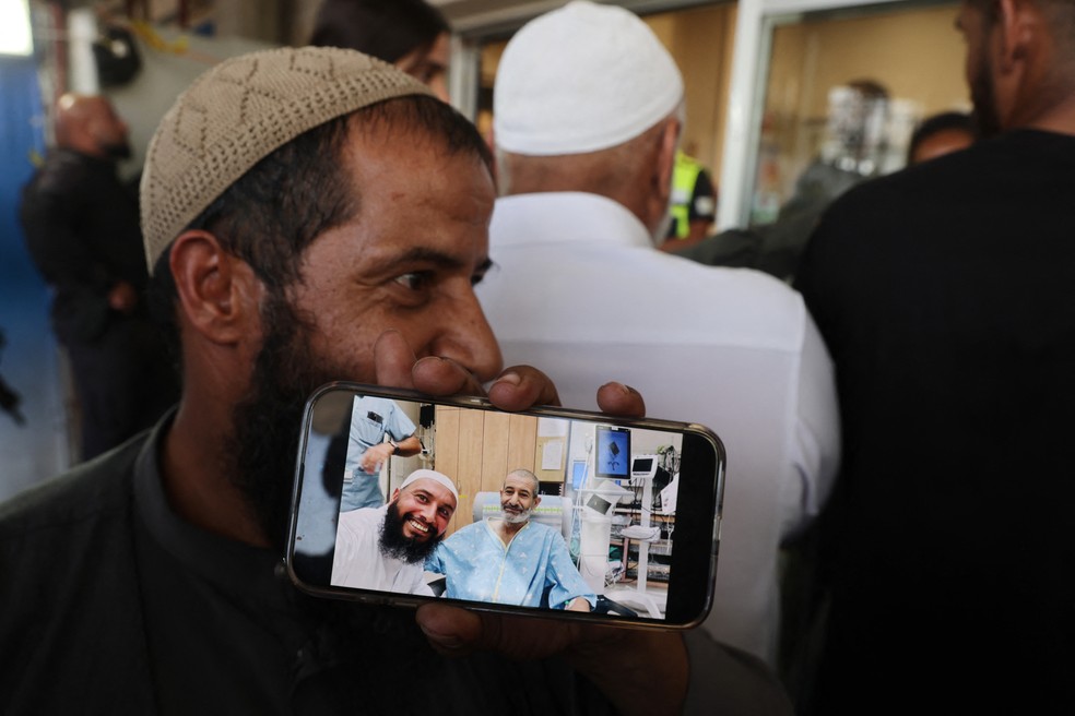 Irmão do refém israelense Kaid Farhan Elkadi, de 52 anos, mostra uma foto dele com outro irmão após resgate — Foto: Menahem KAHANA / AFP