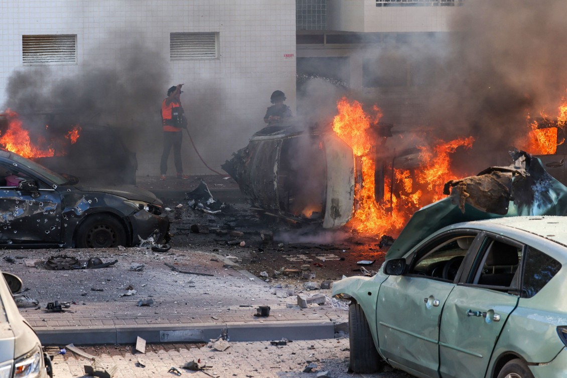 Forças de segurança israelense tenta apagar carros em chamas após um ataque com foguetes da Faixa de Gaza – Ahmad GHARABLI / AFP