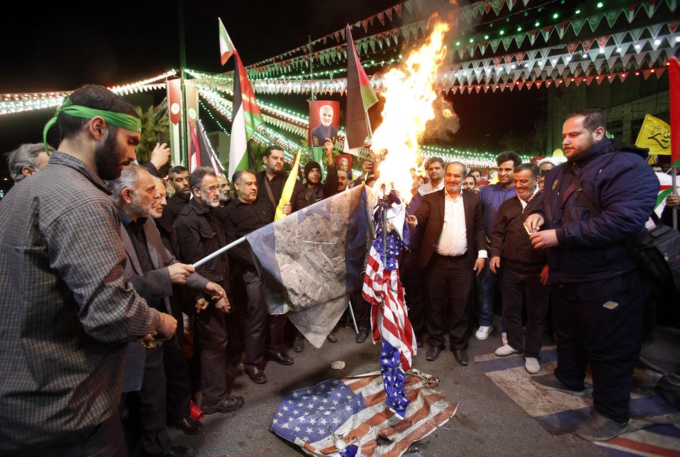 Iranianos queimam bandeiras dos EUA e de Israel em protesto em Teerã após ataque a consulado do país na Síria — Foto: AFP