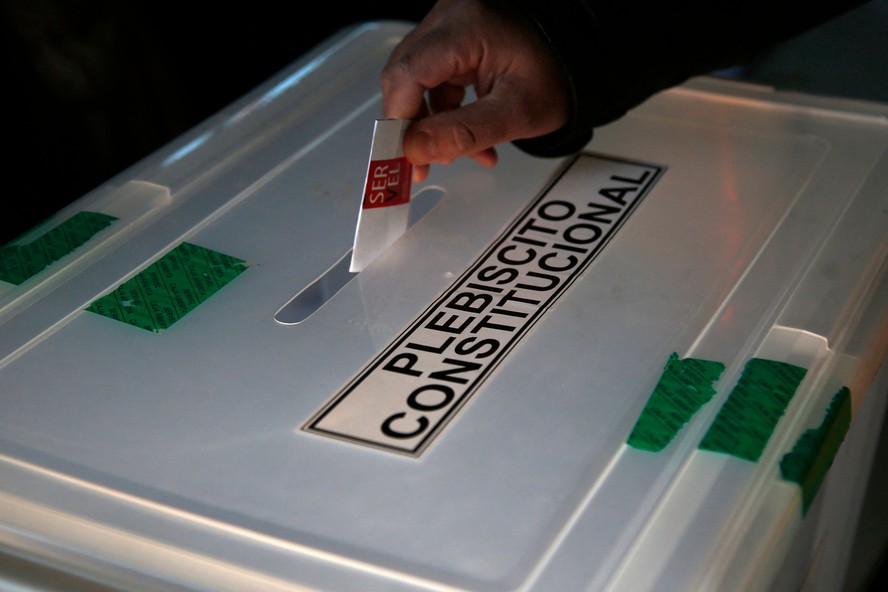 Eleitor deposita voto sobre proposta de nova Constituição do Chile em urna.