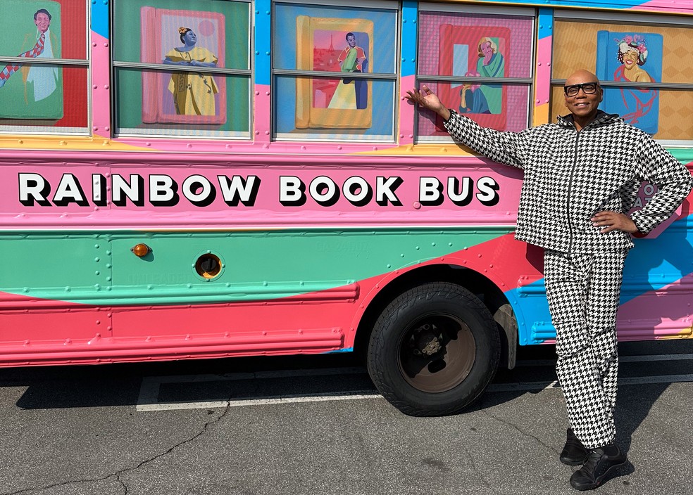 RuPaul ao lado do ônibus escolar nas cores do arco-íris que vai viajar pela Costa Oeste e Sul dos EUA para distribuir livros que foram alvo de censura — Foto: Divulgação / NYT