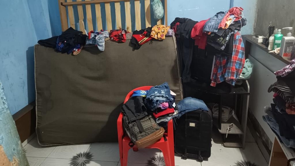 Foto de quarto mostra roupas dobradas, mochila e itens pessoais espalhados. — Foto: Reprodução