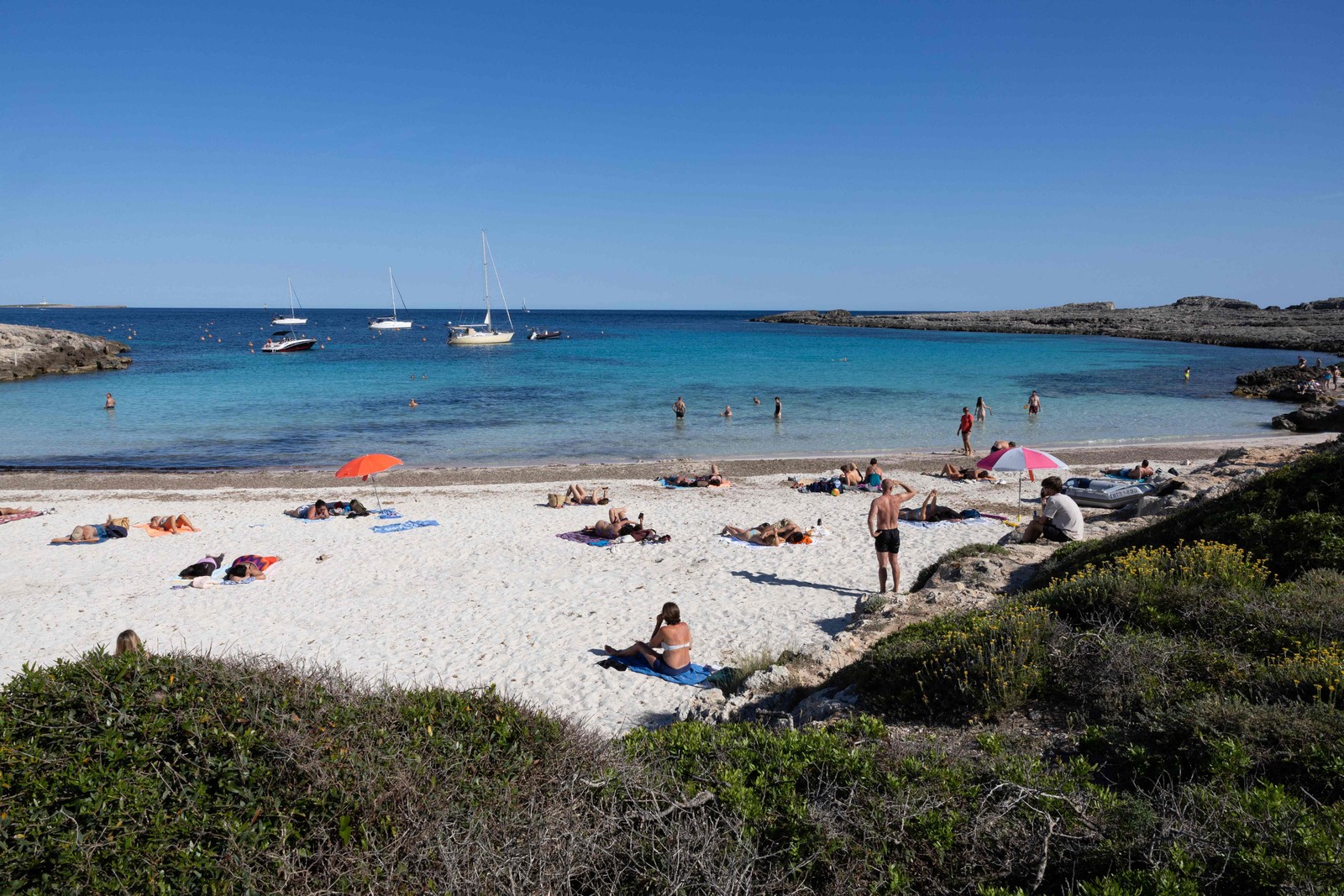 Turistas aproveitam a praia que fica fora da área com horário de visitação restrito de Binibeca Vell, na ilha de Menorca, Espanha — Foto: Jaime Reina / AFP