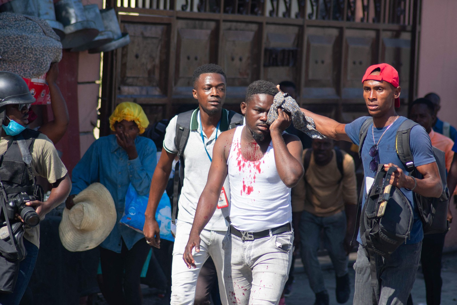 Um jornalista ferido é ajudado após ter sido atingido por uma bomba de gás lacrimogêneo disparada pela polícia em Porto Príncipe, Haiti. — Foto: Clarens SIFFROY / AFP