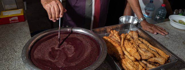 No mercado Ver-o-Peso, peixe frito é servido com açaí em sua forma aveludada e saborosa de acompanhamento, em Belém do Pará — Foto: Alessandro Falco/The New York Times