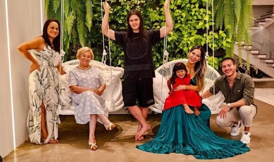 Arthur Aguiar, do 'BBB' 22, com a mulher, Maíra Cardi, a filha, Sophia, e familiares nos balanços da sala da mansão