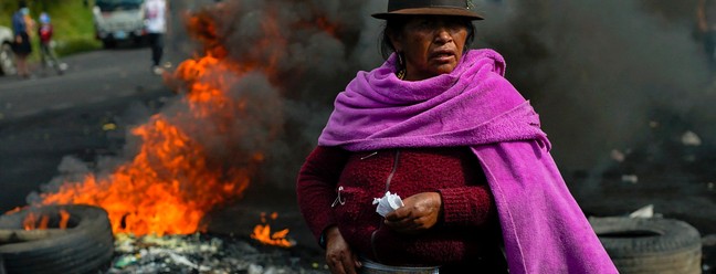 Mulher indígena participa de bloqueio em estrada para protestar contra alta nos combustíveis, no sul de Quito, Equador — Foto: VERONICA LOMBEIDA / AFP