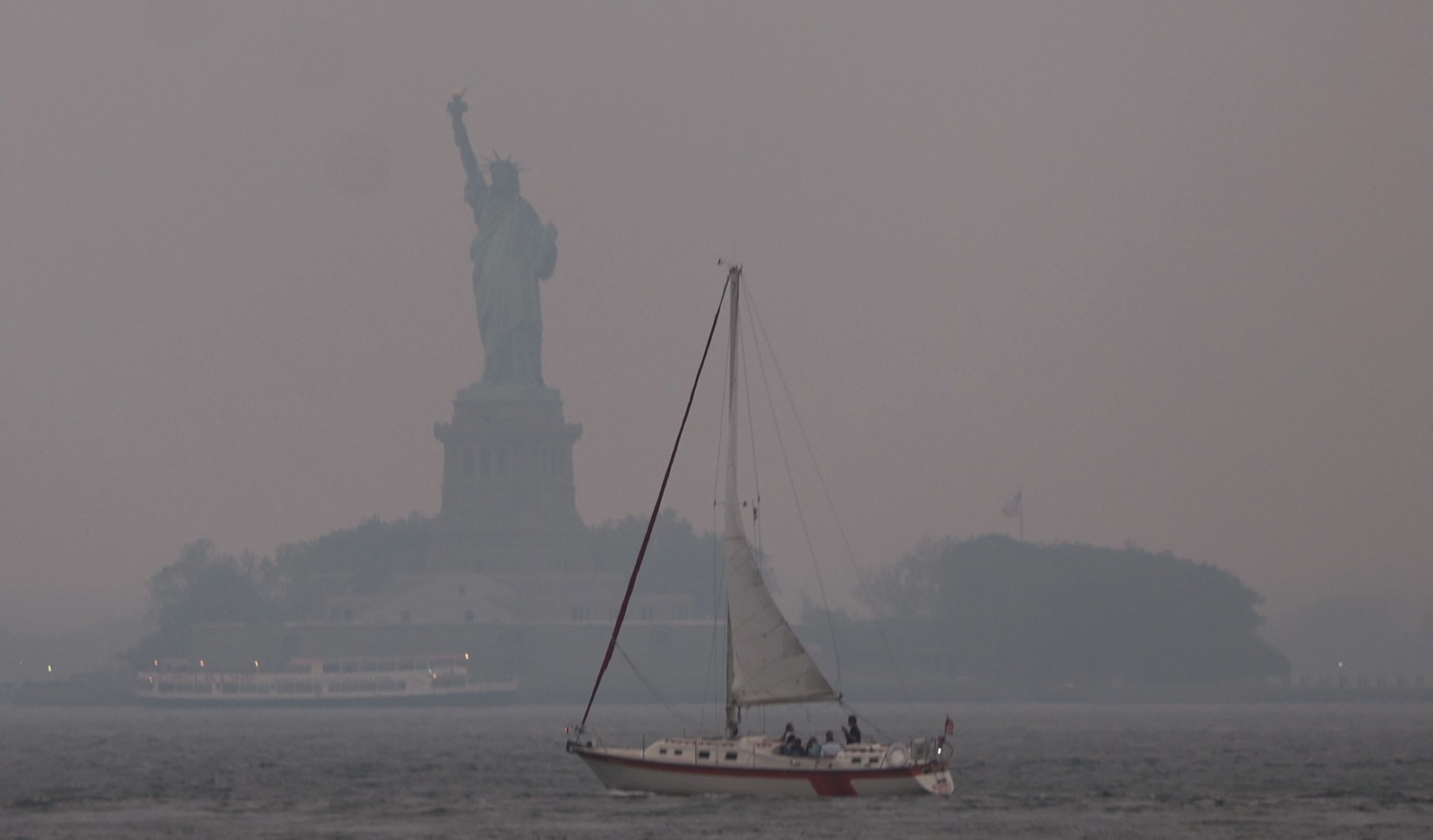 Estátua da Liberdade envolvida por névoa avermelhada, resultado dos incêndios florestais canadenses -  Foto SPENCER PLATT/GETTY IMAGES NORTH AMERICA/Getty Images via AFP