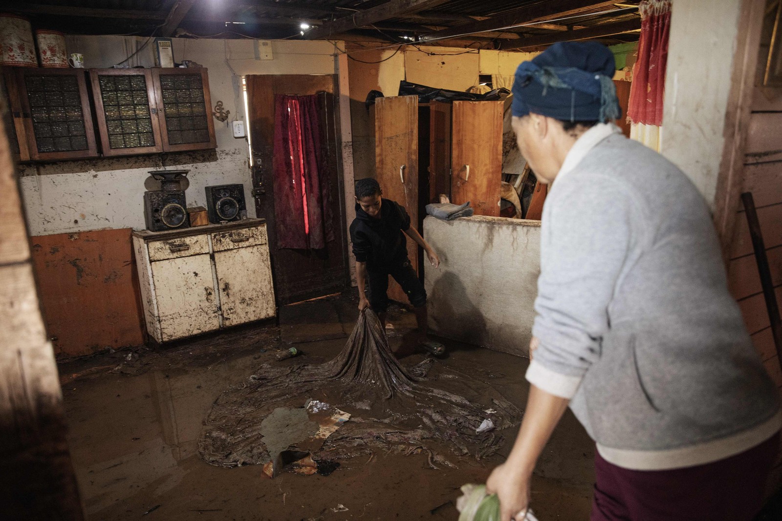 Moradores limpam as águas das enchentes de suas casas. As enchentes causadas por chuvas torrenciais e ventos fortes na costa leste da África do Sul mataram pelo menos 22 pessoas, disseram as autoridades locais na terça-feira. As inundações atingiram vários locais em duas províncias do leste, dois raros tornados foram detectados, as temperaturas caíram e a neve caiu em algumas regiões centrais. — Foto: GIANLUIGI GUERCIA/AFP