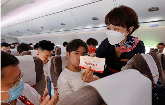 Passageiro tira fotos do cartão de embarque durante o primeiro voo comercial do jato de passageiros C919,  produzido na China