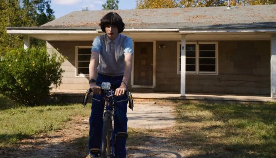 Cena de 'Stranger Things' com a casa dos Byers ao fundo