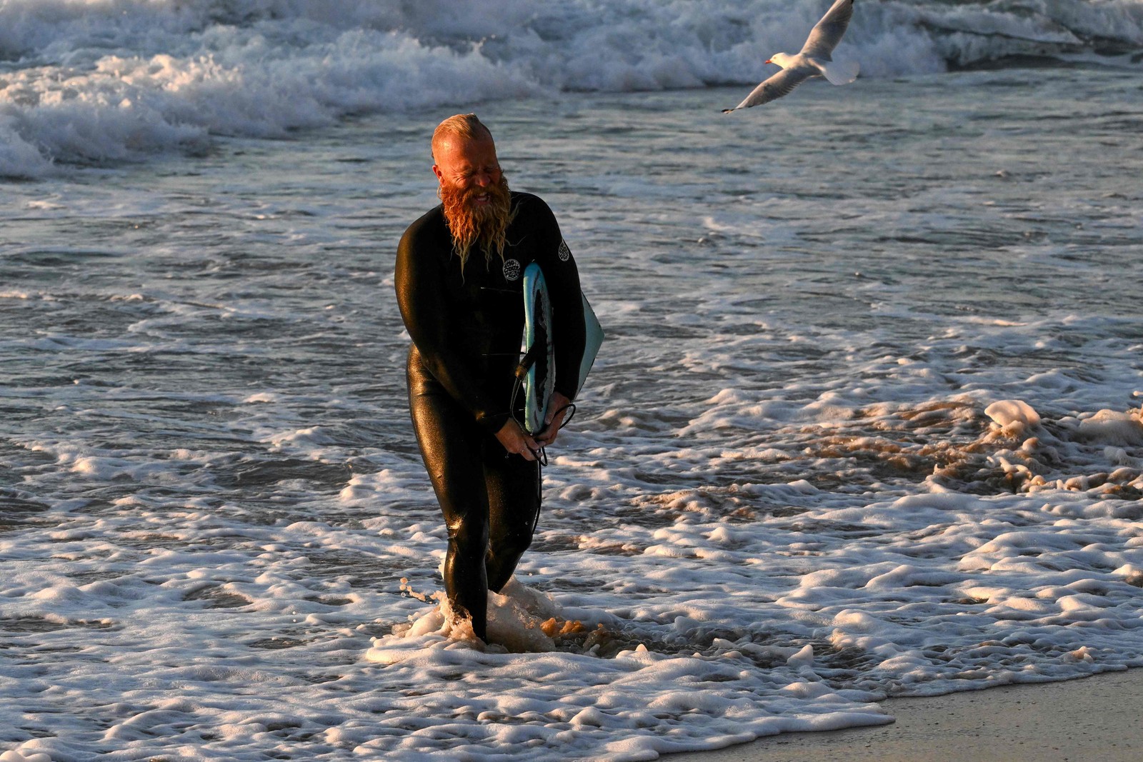 O ex-surfista profissional australiano Blake Johnston caminha de volta à praia depois de quebrar o recorde da sessão de surf mais longa do mundo em Cronulla Beach, em Sydney, em 17 de março de 2023 — Foto: Saeed Khan / AFP