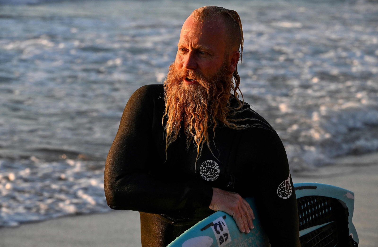 O ex-surfista profissional australiano Blake Johnston depois de quebrar o recorde da sessão de surf mais longa do mundo na praia de Cronulla, em Sydney, em 17 de março de 2023 — Foto: Saeed Khan / AFP