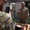 O militar e influenciador ucraniano Ruslan Mokrytskyi cozinha macarrão enquanto seu colega soldado grava um vídeo dele para o Tik Tok em um local não revelado na região de Donetsk, em 27 de julho de 2024 - ANATOLII STEPANOV/AFP