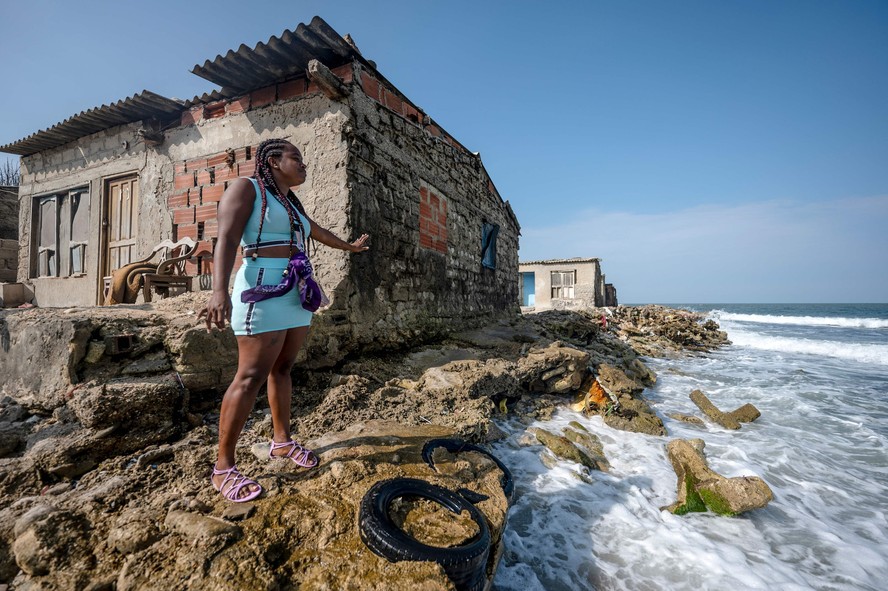 Mulher mostra sua casa afetada pelo aumento do nível do mar em Tierra Bomba Island, Cartagena, na Colômbia.