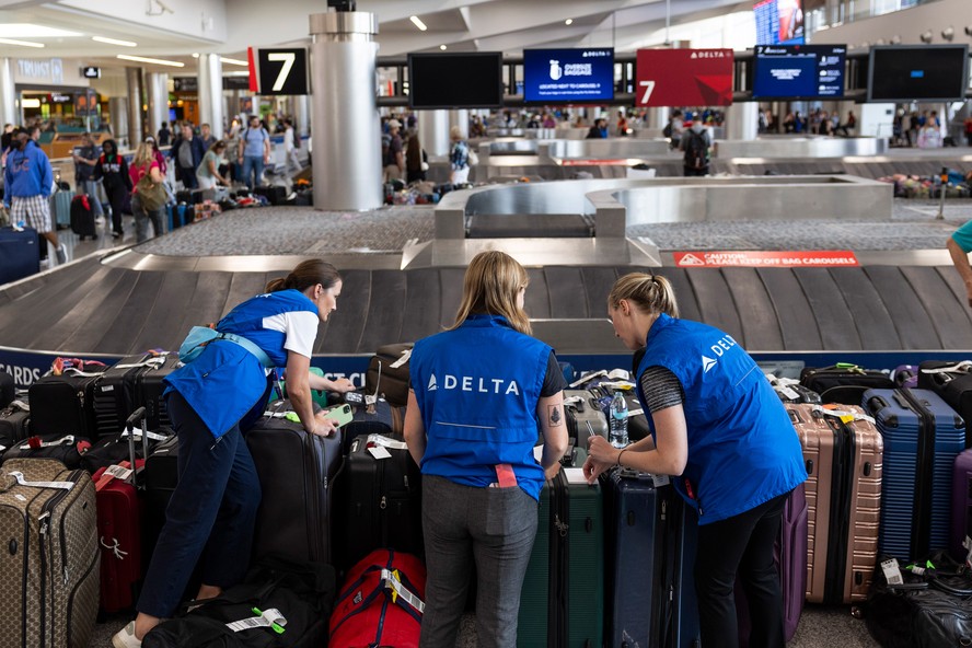 Trabalhadores separam as bagagens na área de esteira da Delta no Aeroporto Internacional Hartsfield-Jackson Atlanta em Atlanta, Geórgia, EUA