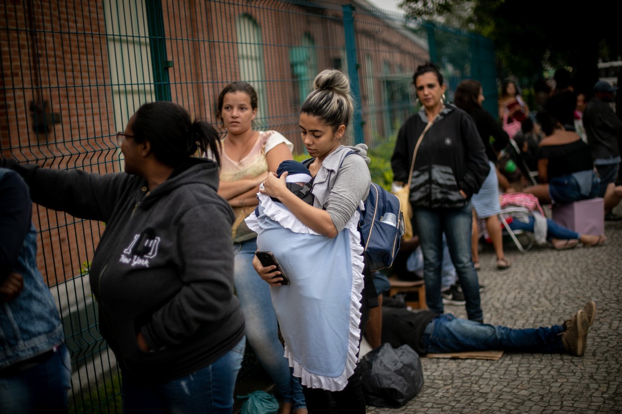 Jennifer Debora do Nascimento, de 26 anos, teve que levar o filho para a fila de recadastramento — Foto: Brenno Carvalho/Agência O Globo