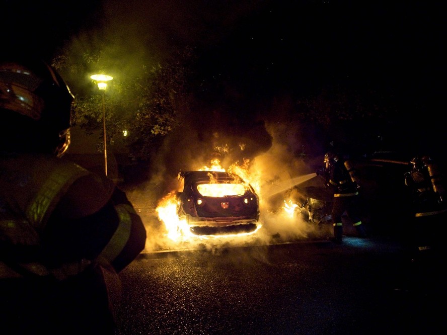 Bombeiros tentam conter chamas de carro incendiado durante protesto em Nanterre, no subúrbio de Paris