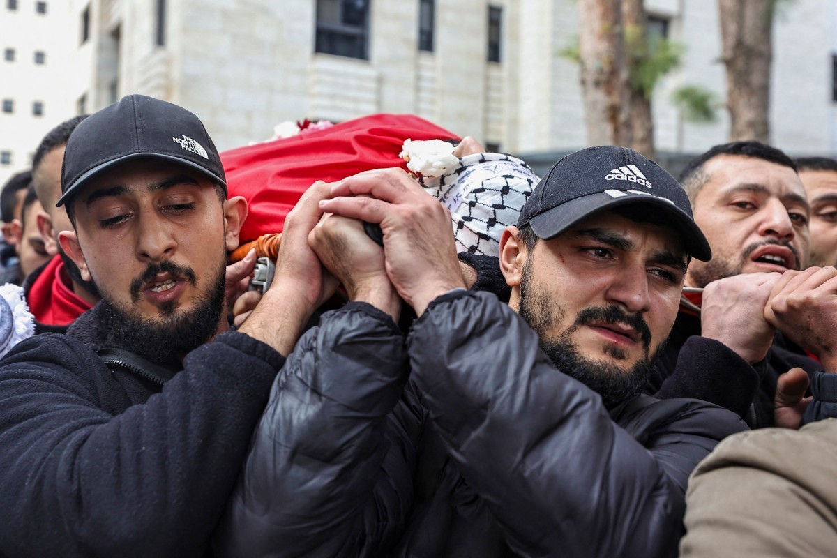 Palestinos em luto carregam o corpo de jovem morto durante ataque noturno das forças israelenses em Ramallah, na Cisjordânia ocupada — Foto: ZAIN JAAFAR/ AFP