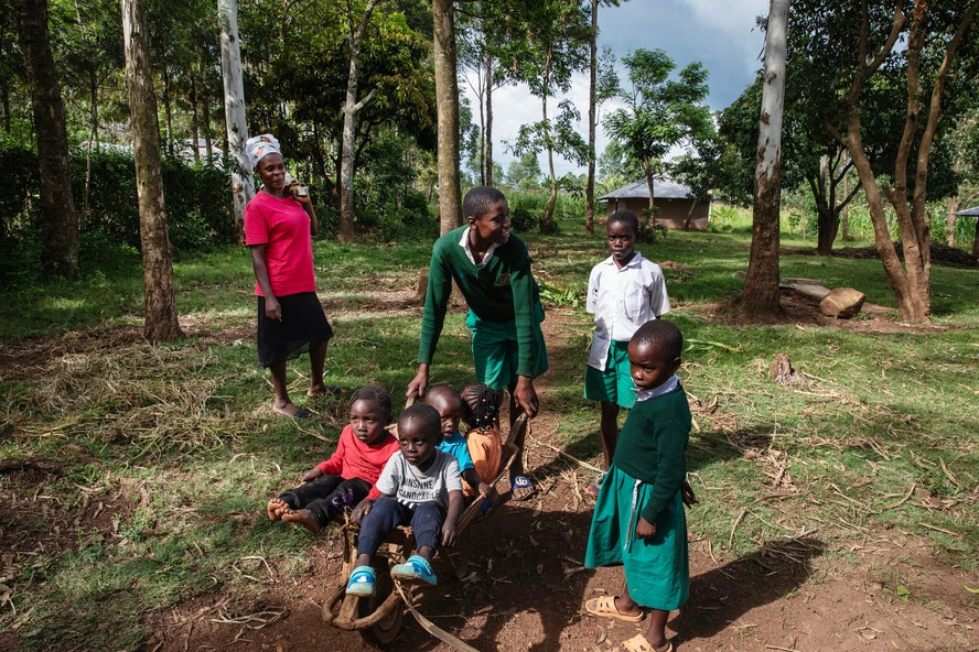 Joyce Achieng, à esquerda, com seus filhos e outras pessoas em sua casa em um vilarejo fora de Migori. Ela tem lutado para conseguir tratamento para dois que têm HIV