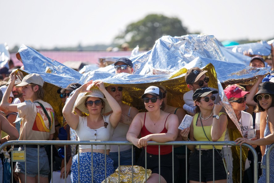 Pessoas se protegem do calor enquanto assistem ao show da banda pop-rock americana Imagine Dragons no Chateau de Chambord em Chambord, centro da França