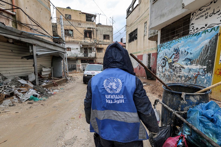 Catador de lixo veste casaco com logo da UNRWA em Jenin