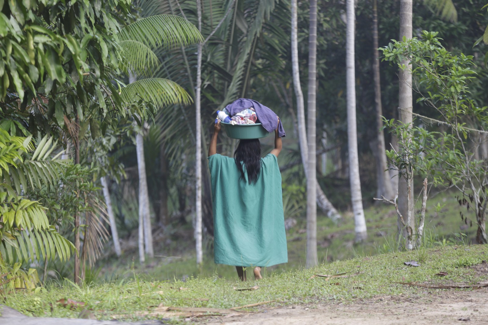 Uma mulher ashaninka durante a lavagem de roupa próxima de um açude — Foto: Domingos Peixoto / Agência O Globo