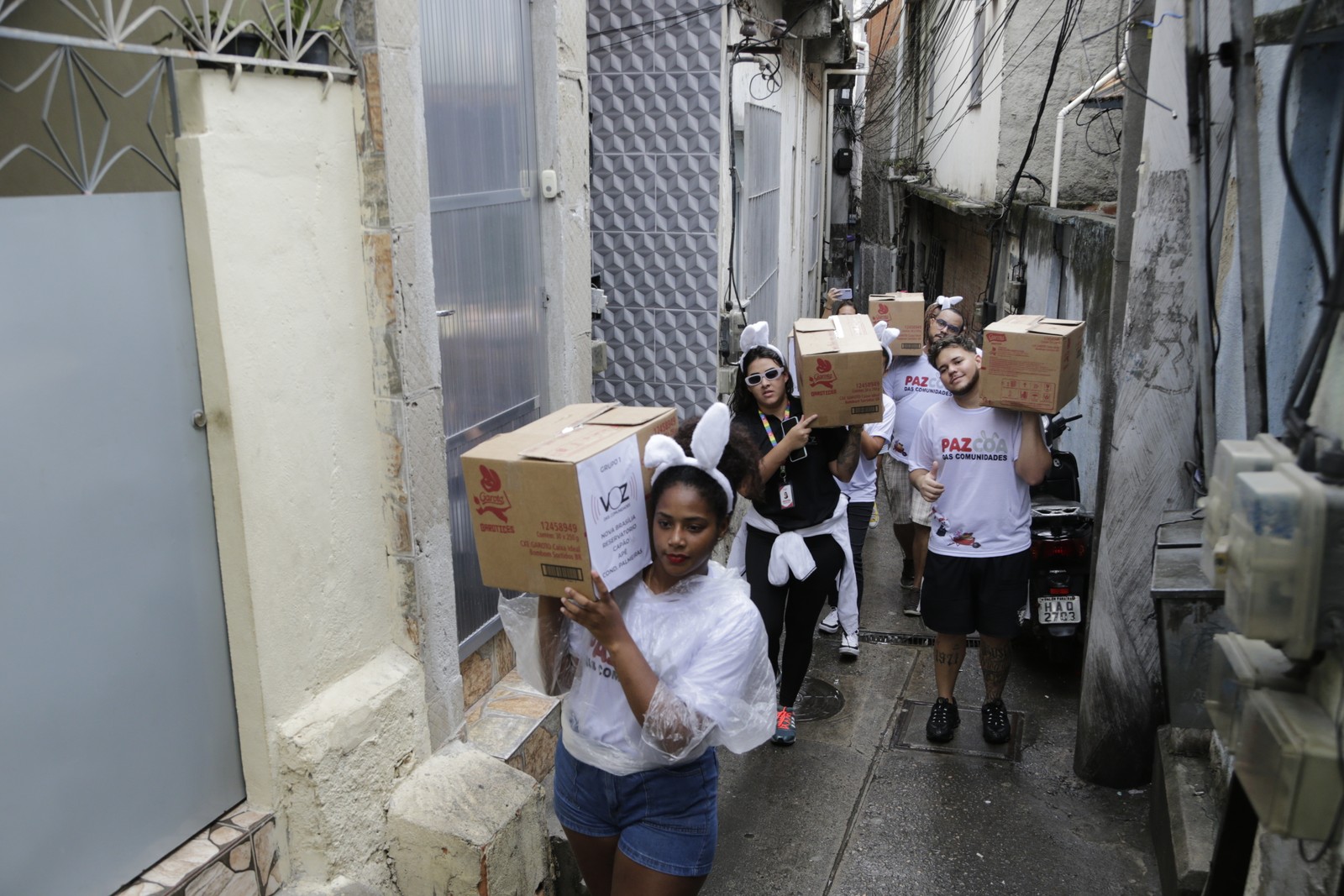 Voluntários carregam caixas de chocolates pelas vielas das comunidades