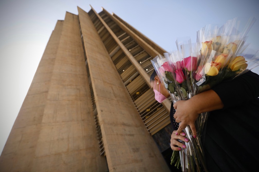 Mulher distribui flores na sede da Caixa em protesto por denúncias de assédio sexual — Foto: Cristiano Mariz