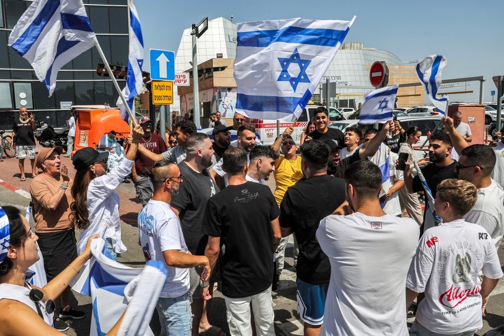 Pessoas se reúnem com bandeiras de Israel em frente ao Centro Médico 'Sheba' Tel-HaShomer. — Foto: JACK GUEZ/AFP