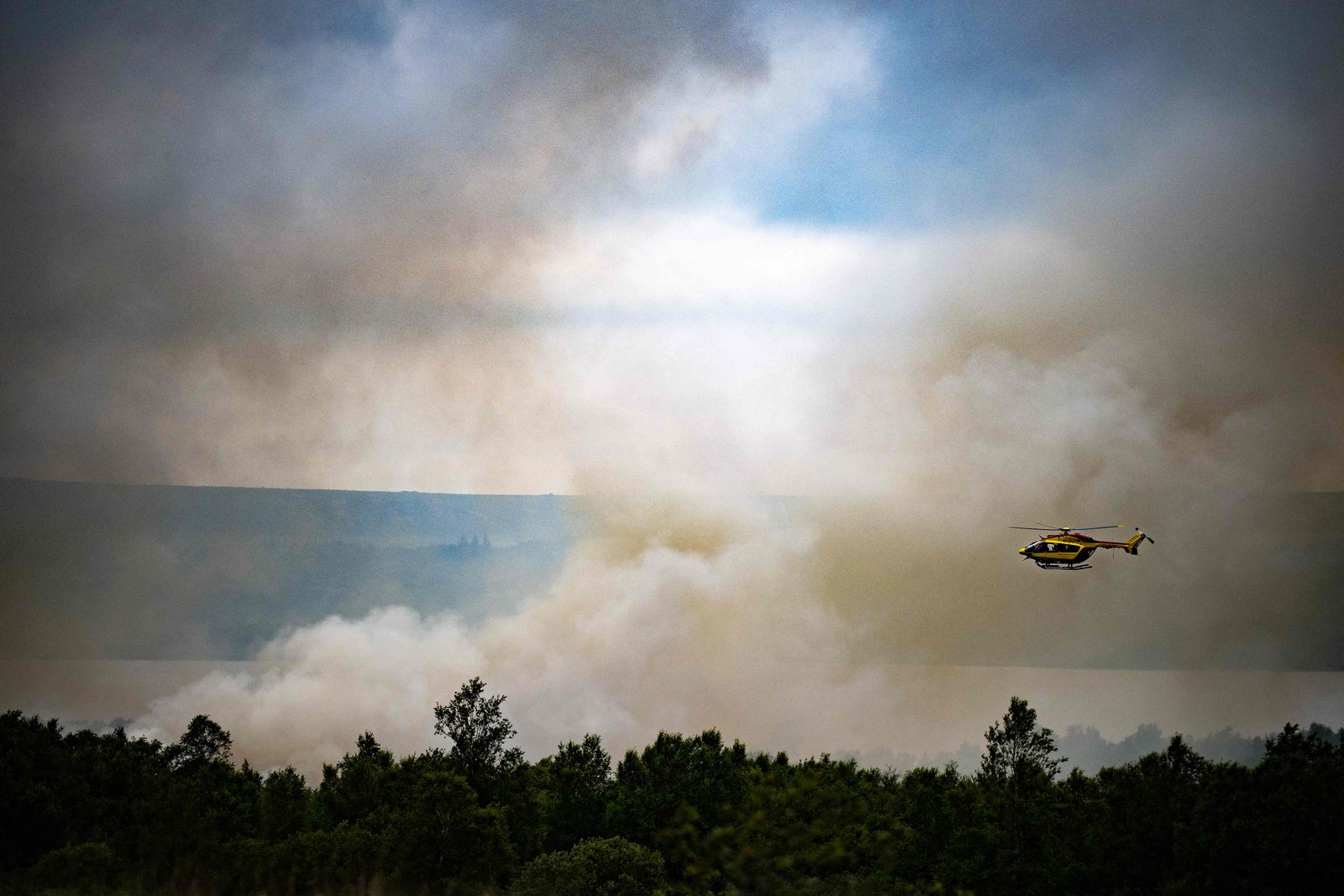 Helicóptero de segurança civil sobrevoa um incêndio florestal em Monts d'Arree, na Bretanha francesa. Onda de calor alimenta incêndios florestais ferozes na Europa  — Foto: LOIC VENANCE / AFP