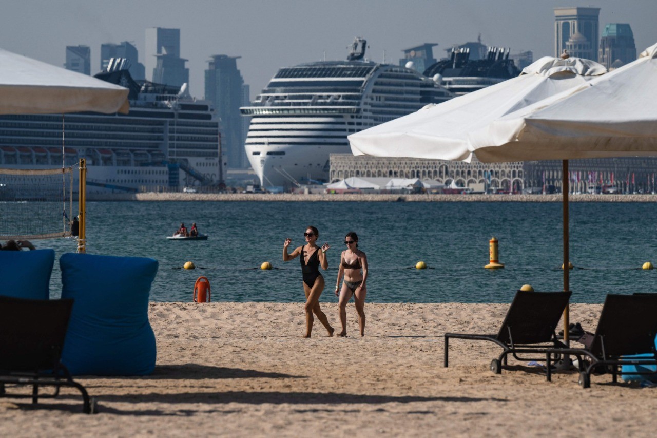 Mulheres caminham na praia de Gas Abou Abboud, em Doha, onde há iates de luxo ancorados — Foto: ANDREJ ISAKOVIC / AFP