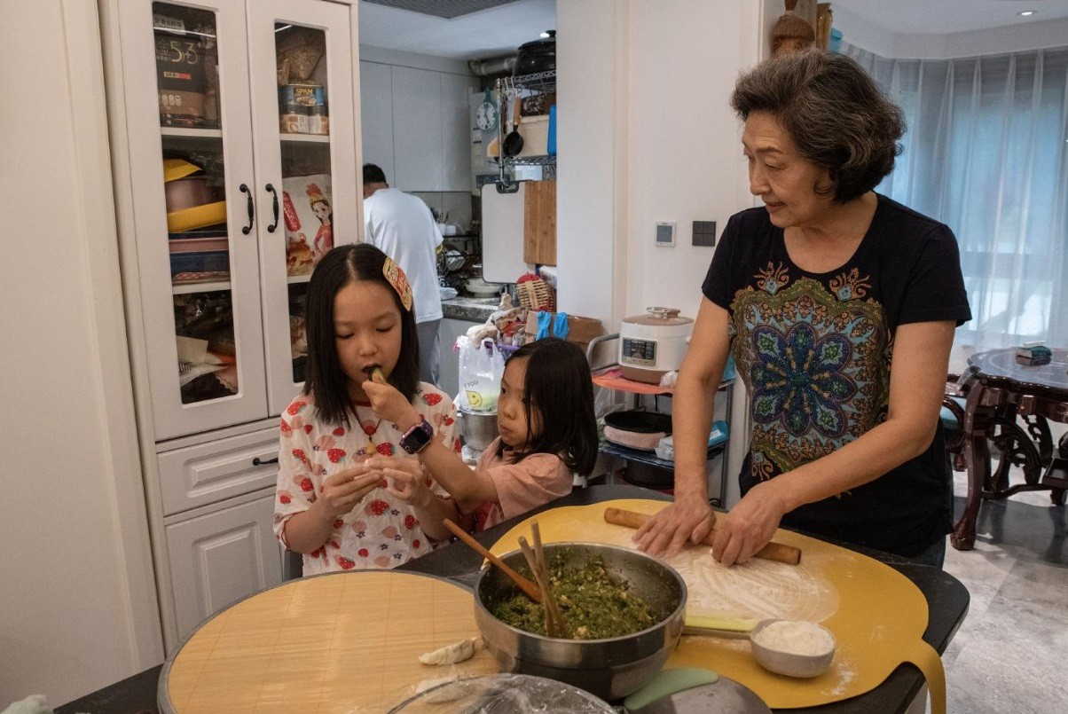 Sun Yang, do Glamma Beijing, em casa, prepara uma refeição ao lado das netas — Foto: Gilles Sabrié/NYT