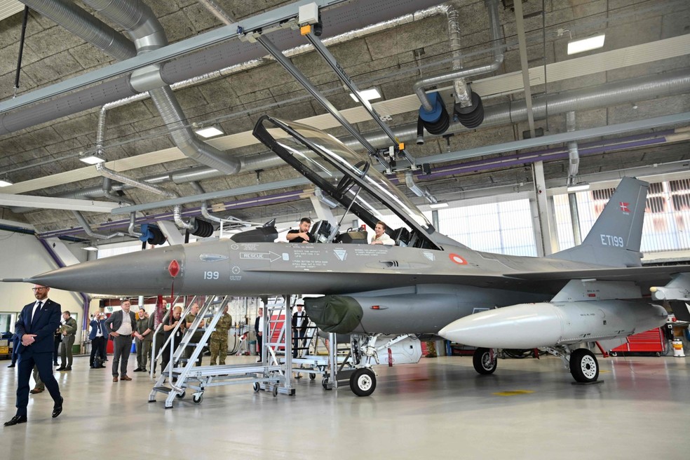 Zelensky (à esquerda) e a primeira-ministra dinamarquesa Mette Frederiksen sentam-se em um caça F-16 no hangar da base aérea de Skrydstrup em Vojens, norte da Dinamarca — Foto: Sergei GAPON / AFP