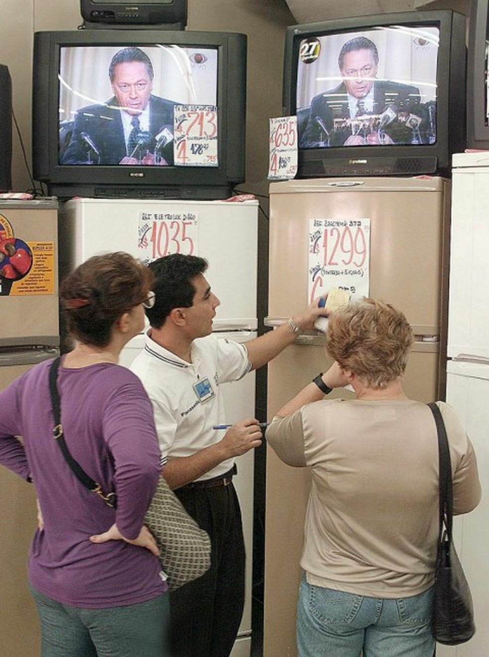Clientes na loja de eletrodomésticos enquanto o ministro Pedro Malan fala sobre cortes no Orçamento — Foto: Antônio Scorza