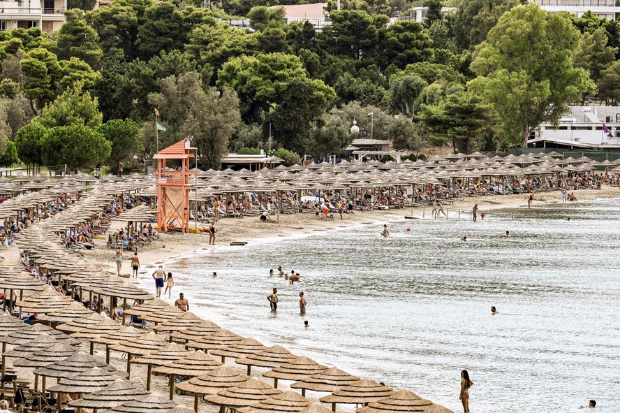 Banhistas tentam um espaço na areia tomada por barracas na praia de Oceanis, em Vouliagmeni, a 25km de Atenas, na Grécia