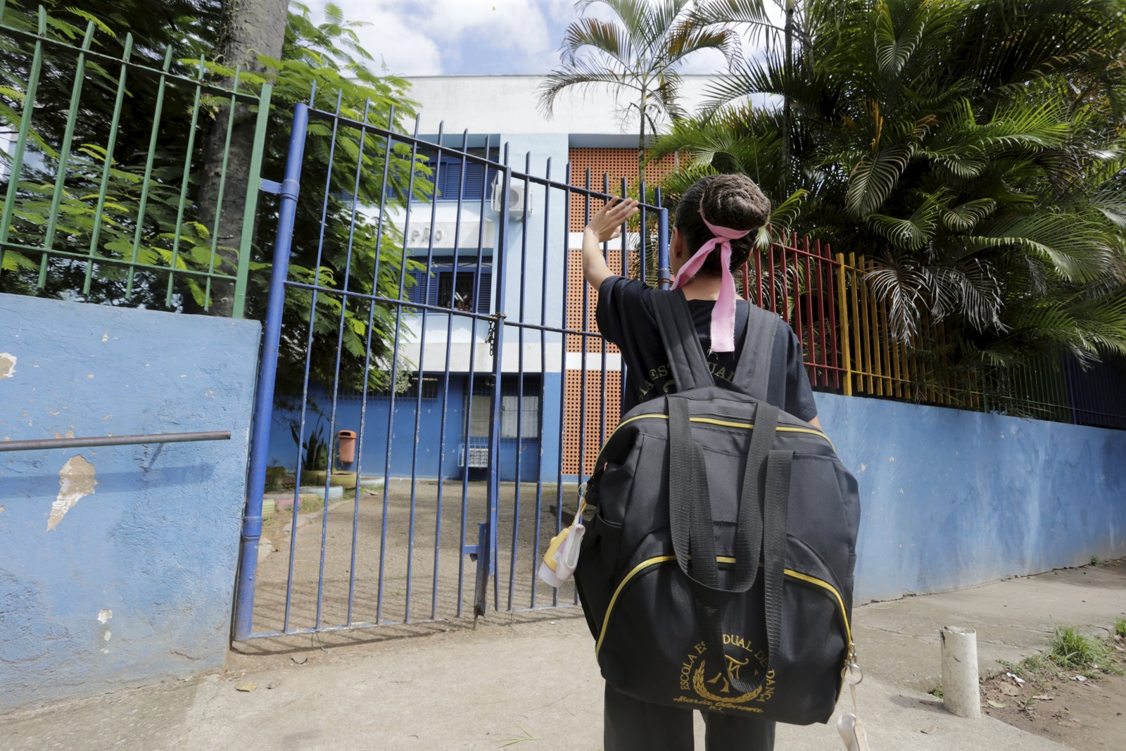 Começo do percurso. Depois da aula na escola municipal, Alice se despede dos coleguinhas que dão 'tchau' pela janela; carro de aplicativo a espera para buscar as amigas em outro colégio