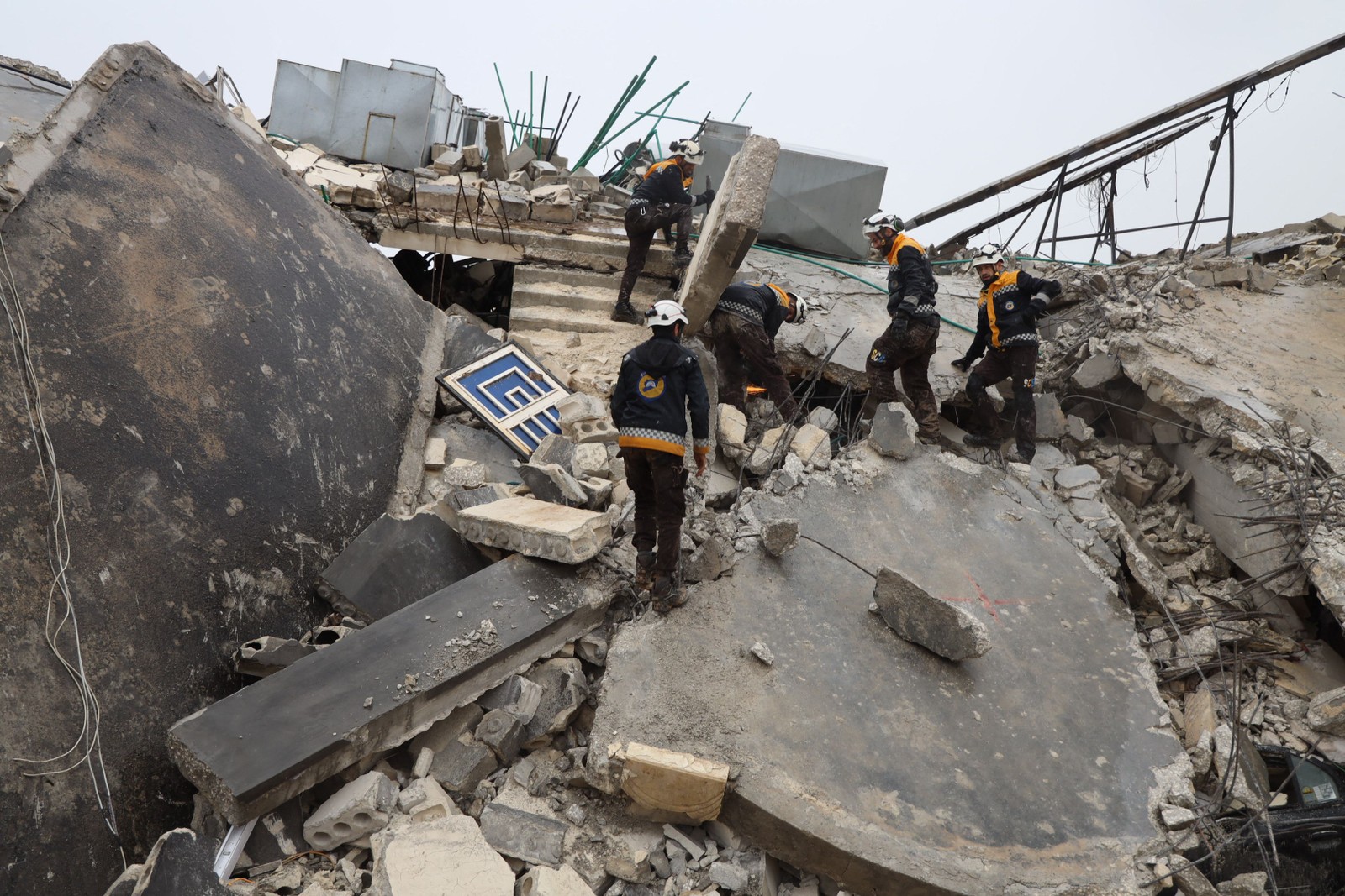 Membros da defesa civil síria, conhecidos como Capacetes Brancos, procuram vítimas sob os escombros após um terremoto na cidade de Sarmada, no interior da província de Idlib, em 6 de fevereiro de 2023 — Foto: Mohammed Al-Rifai / AFP