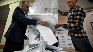 Membros de uma comissão eleitoral esvaziam uma urna em uma seção eleitoral após o último dia da votação em Moscou — Foto: Alexander NEMENOV / AFP