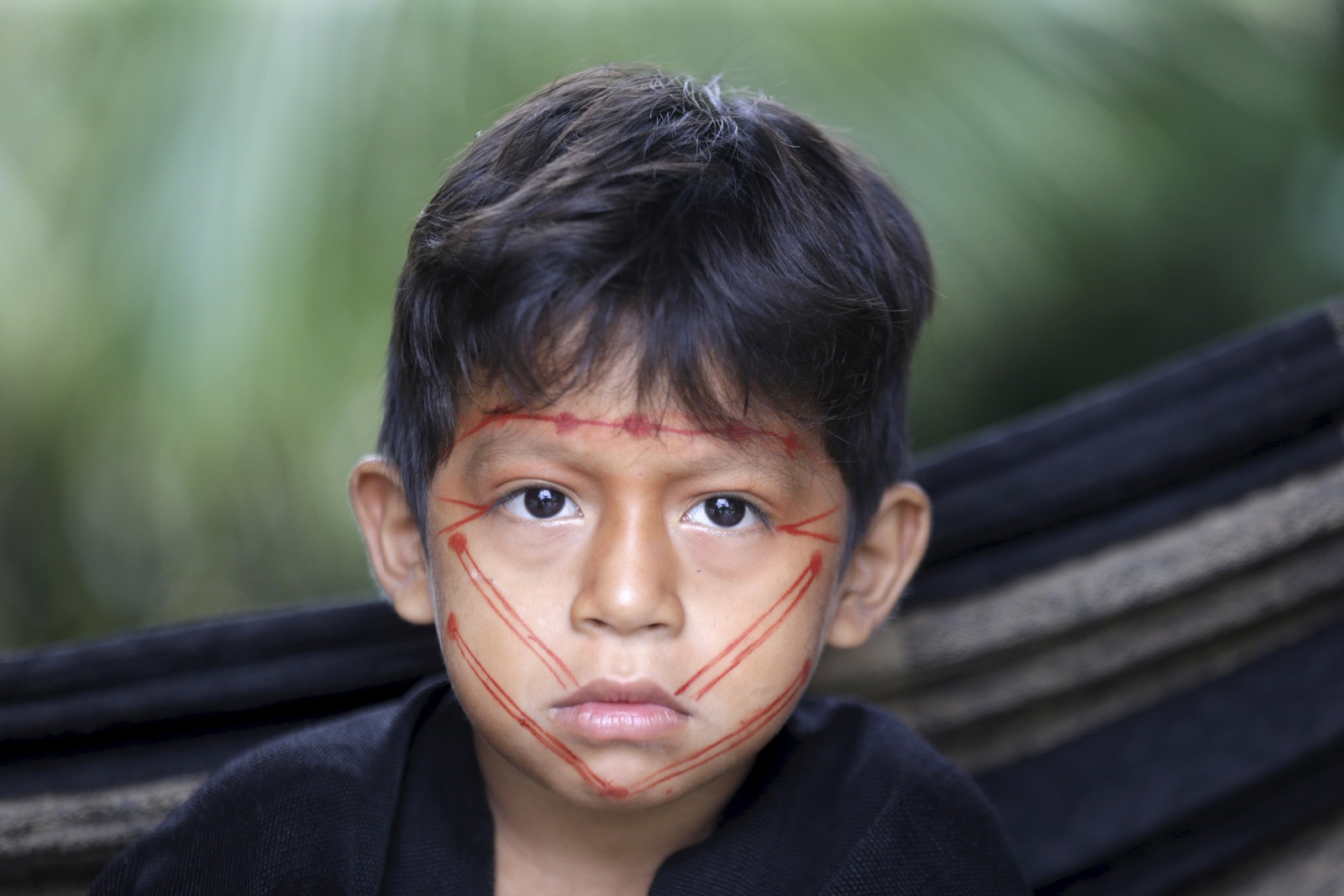 As crianças ashaninkas aprendem desde cedo a pilotar embarcações e a construir pequenas casas para  morar. O filho de Enison Pyãko brinca com os irmãos próximo à rede — Foto: Domingos Peixoto / Agência O Globo