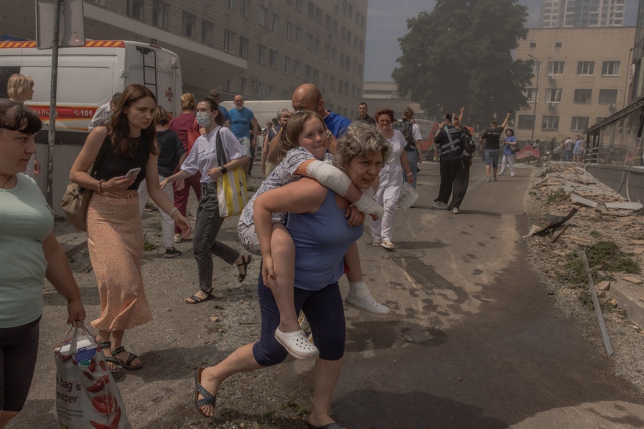 Mulher carrega uma menina nas costas após bombardeio russo atingir o Hospital Infantil Okhmatdyt, o maior da Ucrânia; Rússia lançou mais de 40 mísseis em várias cidades do país — Foto: Roman Pilipey/AFP