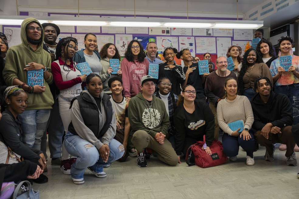 Estudantes exibem cópias do novo livro de Tommy Orange, “Wandering Stars”, enquanto posam para uma foto com o autor (ao centro), na Millennium Art Academy no Bronx — Foto: Hiroko Masuike/The New York Times