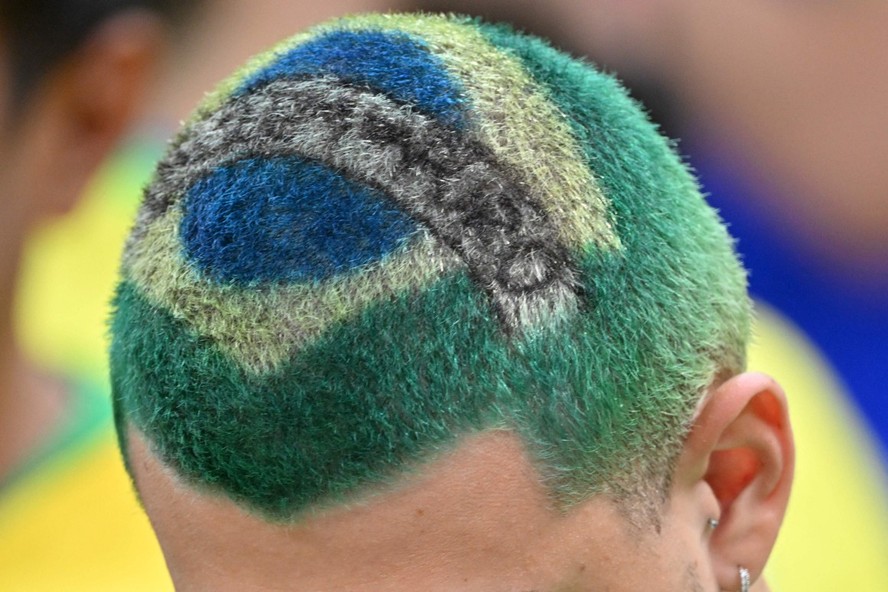 Torcedor do Brasil exibe a bandeira do país desenhada em seu cabelo antes da partida entre Camarões e Brasil, no Estádio Lusail