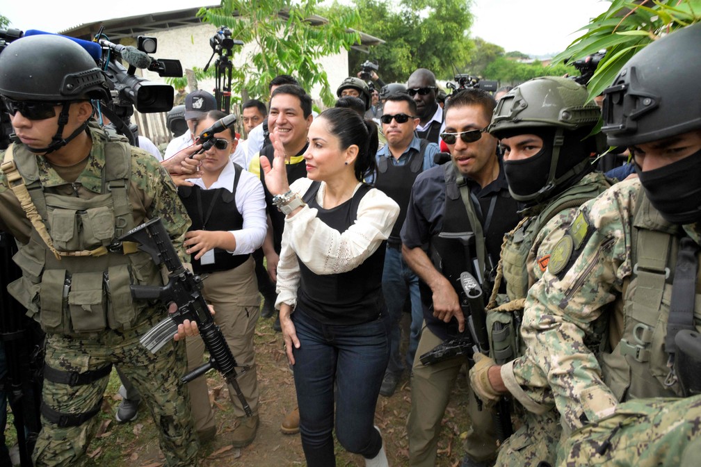 Cercada por militares, a candidata presidencial do Equador pelo Partido Revolución Ciudadana, Luisa Gonzalez usa um colete à prova de balas, acena ao sair após votar em uma seção eleitoral em Canuto, Equador — Foto: Rodrigo BUENDIA / AFP