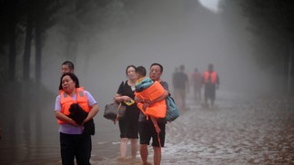 Pessoas deixam uma área inundada após fortes chuvas em Zhuozhou, na província de Hebei, no norte da China.  — Foto: CNS / AFP / China OUT