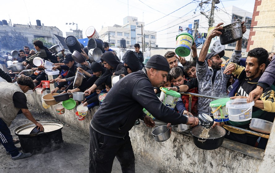 Palestinos coletam alimentos em um ponto de doação em um campo de refugiados em Rafah, no sul da Faixa de Gaza, em 23 de dezembro de 2023, em meio a contínuas batalhas entre Israel e o grupo militante Hamas.