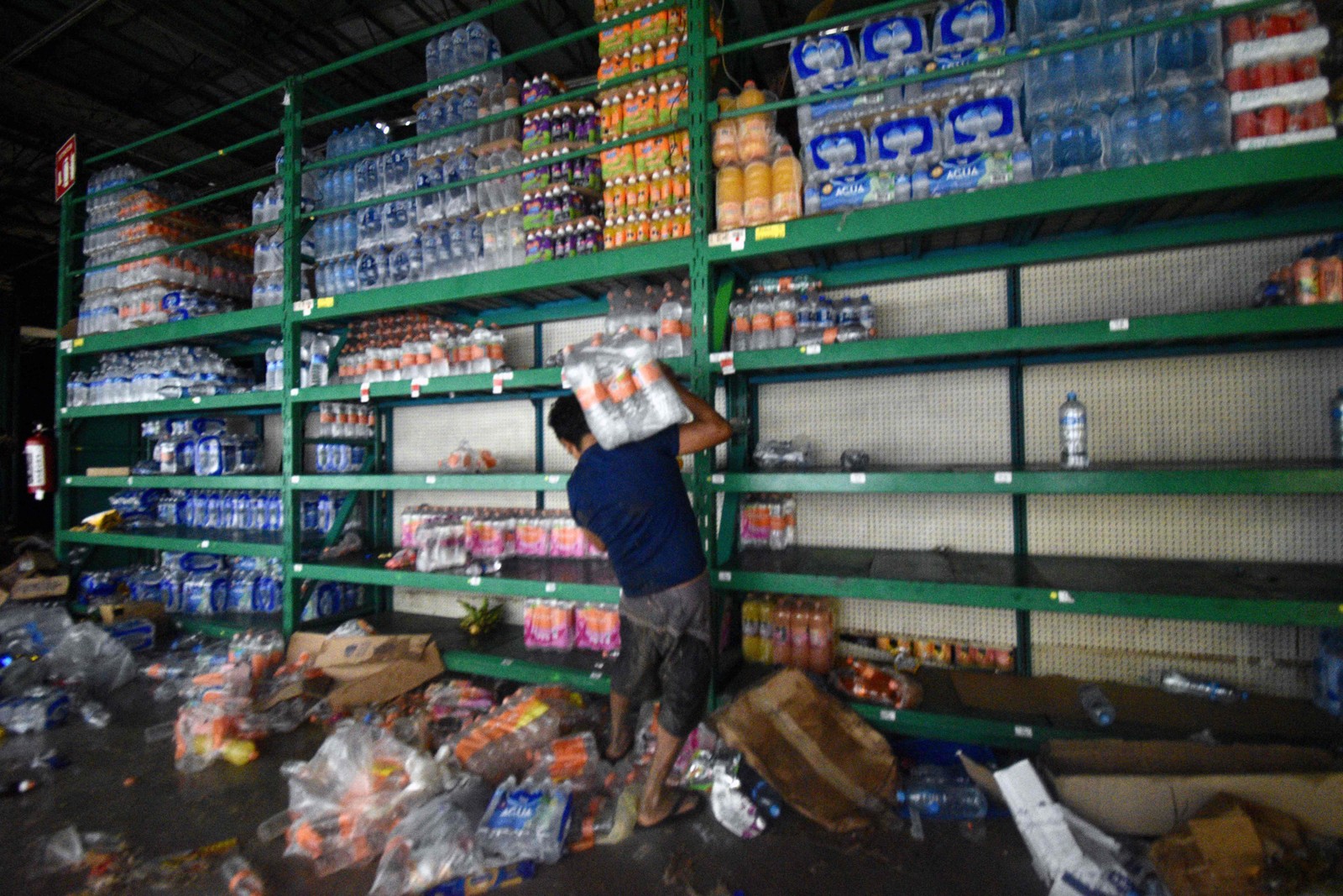 Um homem coleta mantimentos em um supermercado saqueado após a passagem do furacão Otis em Acapulco, estado de Guerrero, México — Foto: HAARON ALVAREZ/AFP