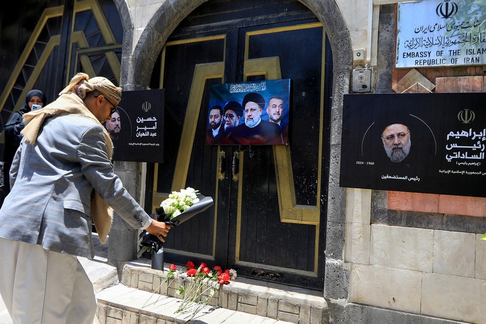 Pessoas prestam homenagem ao presidente iraniano e membros de sua comitiva mortos em um acidente aéreo em frente à Embaixada do Irã em Sanaã, no Iêmen. — Foto: MOHAMMED HUWAIS/AFP