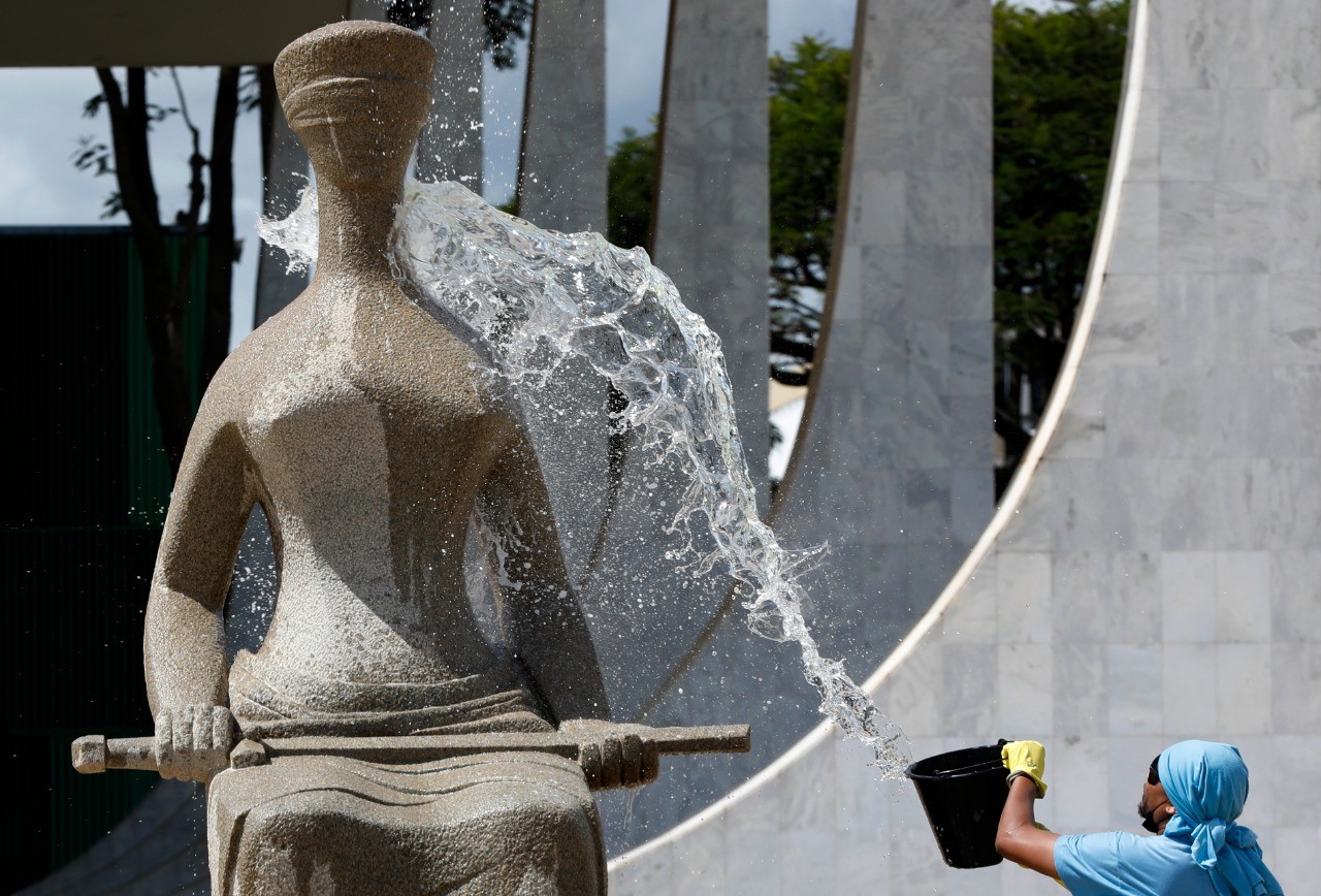 Funcionário da equipe de limpeza do STF limpa estátua que foi pichada por manifestantes — Foto: Cristiano Mariz/Agência O Globo