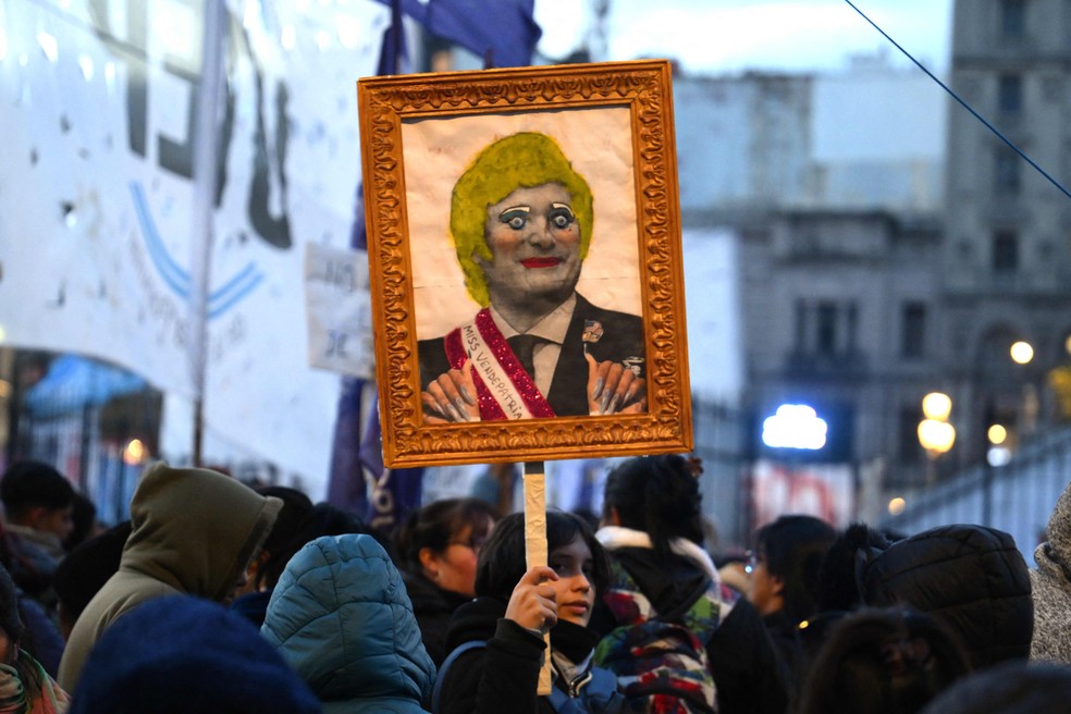 Cartaz crítico ao presidente da Argentina, Javier Milei, é erguido em manifestação contra a violência de gênero na Argentina — Foto: Luis ROBAYO / AFP